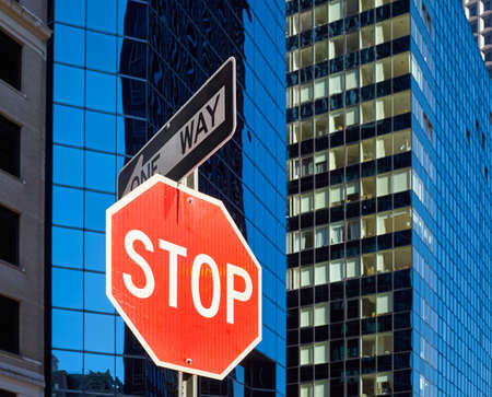 Stop sign on a street of New York City with blurred modern buildings in background, selective focus, USA.の写真素材