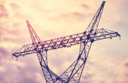 Power transmission tower silhouette at sunset, color toning applied.