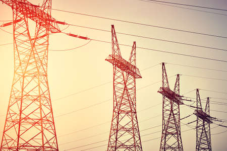 Four power transmission towers silhouettes at sunset, color toning applied.の写真素材