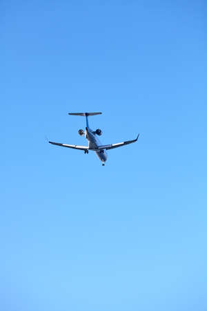 Rear view of a landing plane against the clear blue sky.の写真素材