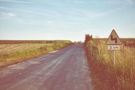 Retro toned picture of a countryside road at sunset, Poland.