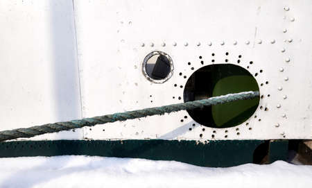 Old ship side with hole and hawser, nautical background.の写真素材