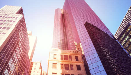 Looking up at skyscrapers against the sun, color toned picture, New York City, USA.