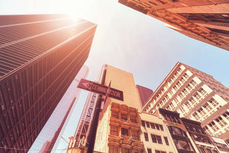 Looking up at Manhattan skyscrapers against the sun, color toned picture, New York City, USA.