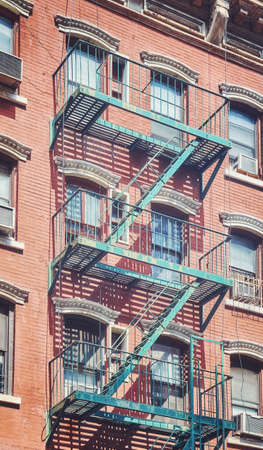 Old brick building with iron fire escape, color toning applied, New York City, USA.