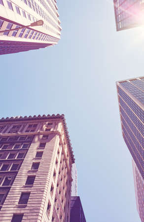 Looking up at New York buildings against the sun, color toned picture, USA.