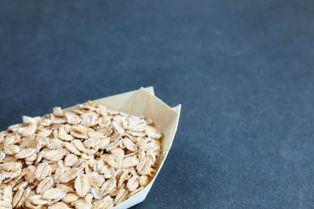 Organic spelt flakes in a wooden eco container, selective focus, space for text.