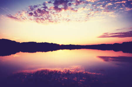 Scenic golden sunset over calm water, color toning applied.の写真素材