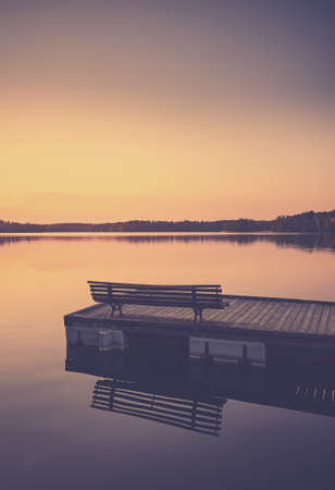 Wooden lake pier at sunset, color toning applied.の写真素材