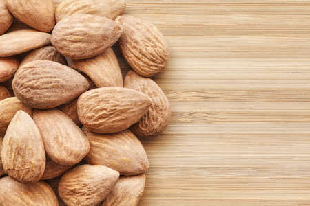 Close up picture of almonds on a wooden background, selective focus.
