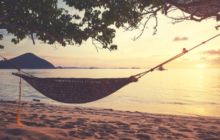 Hammock on the beach of a small island in the Philippines at sunset, color toning applied.の写真素材