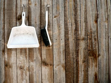 Brush and pan hanging on the side of a weathered barn.の写真素材