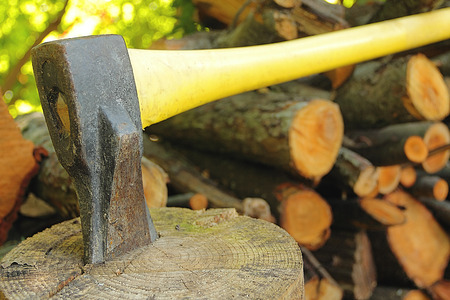 A closeup of an old axe stuck in a log with chopped woodの写真素材