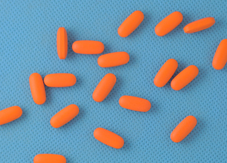 Orange medication scattered across a blue 