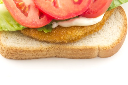 A fresh chicken patty sandwich with tomato, lettuce, and mayo on white breadの写真素材