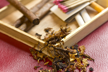 Tobacco, cigarettes, cigars, smoking, etc. on red leather background