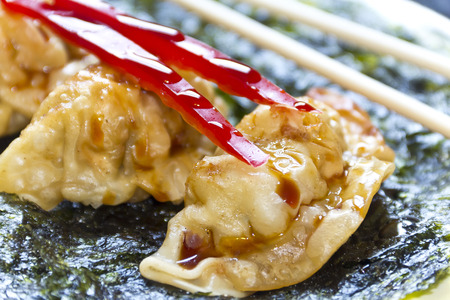 Fried Japanese dumplings on crispy roasted seaweed and red pepper garnishの写真素材