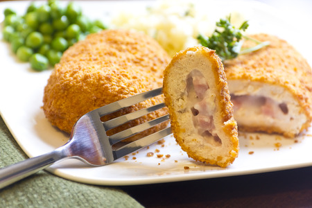 Breaded stuffed chicken cordon bleu with green peas white rice and parsley for garnishの写真素材
