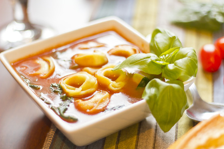 Hearty tortellini tomato soup with spinach and basilの写真素材