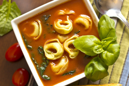 Hearty tortellini tomato soup with spinach and basilの写真素材