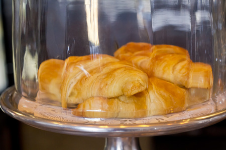 Tasty flaky plain croissants in bakery display caseの写真素材