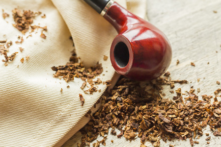 Tobacco pipe on rustic warn wood surface with spilled natural tobaccoの写真素材