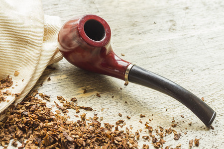 Tobacco pipe on rustic warn wood surface with spilled natural tobaccoの写真素材