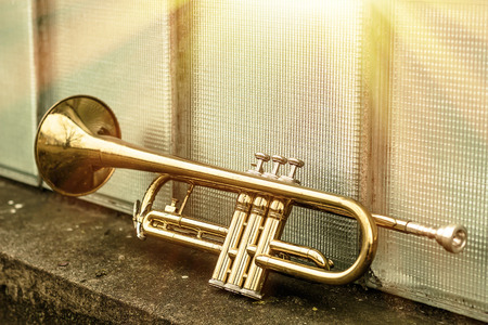 Old worn trumpet stands alone against a window background outside a jazz club