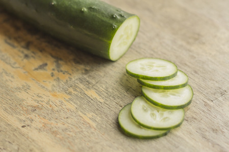 Fresh organic cucumber chopped on distressed table topの写真素材
