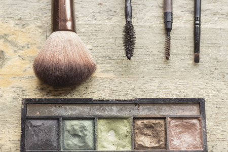 Used makeup kit on distressed wooden surface for beauty and cosmetics themed background