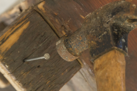Old and worn contracting hammer and three nails on a distressed work benchの写真素材