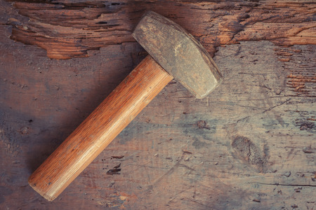 Small single handed worn sledge hammer on grunge wood background Small single handed worn sledge hammer on grunge wood background