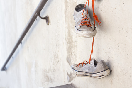 Pair of old worn classic sneakers hanging from railingの写真素材