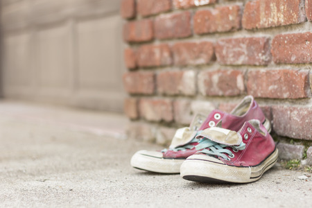 Pair of old worn classic sneakers leaning against a brick wallの写真素材