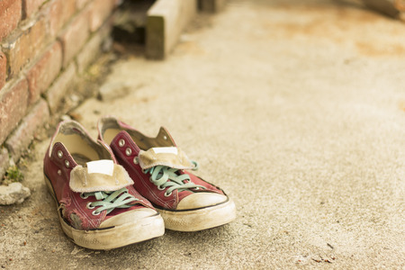 Pair of old worn classic sneakers leaning against a brick wallの写真素材
