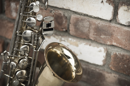 Lone old saxophone leans against brick wall outside abandoned jazz clubの写真素材
