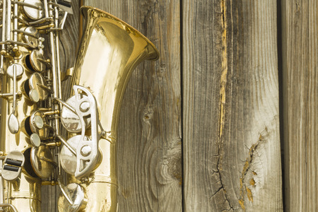 Lone old saxophone leans against wooden fence outside jazz clubの写真素材