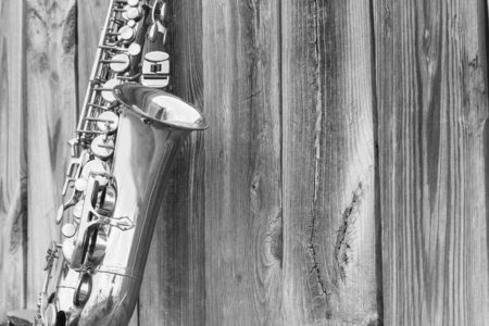 Lone old saxophone leans against wooden fence outside jazz clubの写真素材