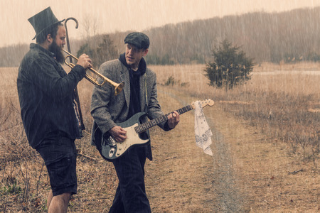 Stylish gypsies play trumpet and electric guitar on a wilderness pathの写真素材