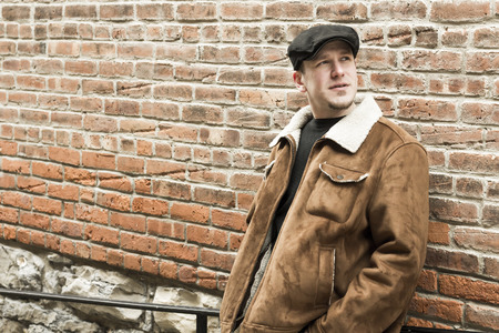 Cool guy rocks an aviator jacket and newsboy cap as he takes a moment to thinkの写真素材