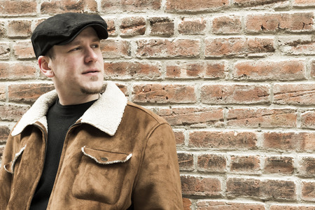 Cool guy rocks an aviator jacket and newsboy cap as he takes a moment to think
