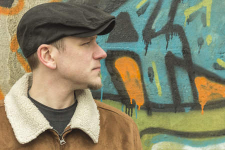 Cool guy rocks an aviator jacket and newsboy cap as he takes a moment to think