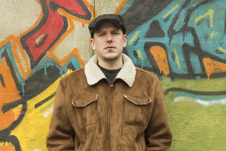Sad guy rocks an aviator jacket and newsboy cap as he takes a moment to think