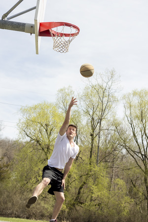Young man doing basketball trick shots as he leaps through the air