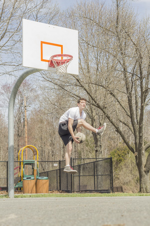Young man doing basketball trick shots as he leaps through the air