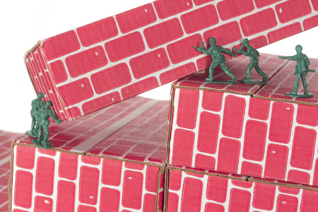 Green army men using teamwork to make progress up the toy brick stairsの写真素材