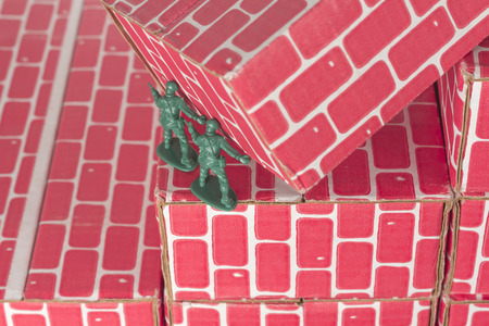 Green army men using teamwork to make progress up the toy brick stairsの写真素材