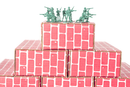 Green army men guarding the top of red cardboard brick baseの写真素材