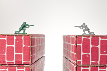 Rival toy army men aim guns at eachother atop opposing toy bricksの写真素材
