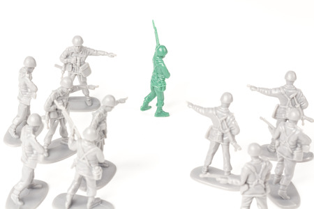 Gray toy soldiers pointing and bullying a green toy soldierの写真素材